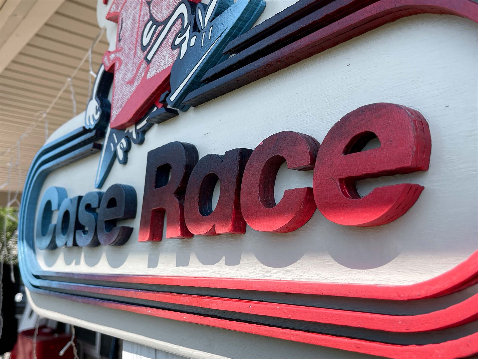 Close-up of the layered Case Race sign showing dimensional painted letters and track stripes