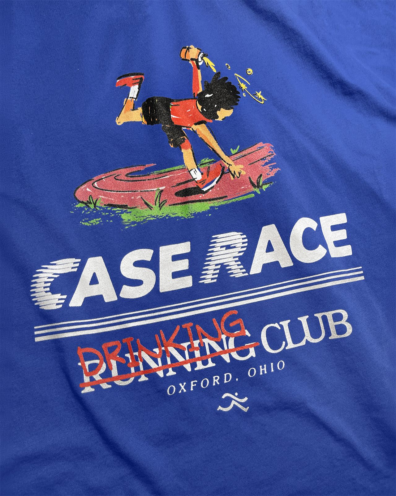 Close-up of the blue tee print, a runner mid-stumble above the Case Race wordmark with Running crossed out and Drinking scrawled over it