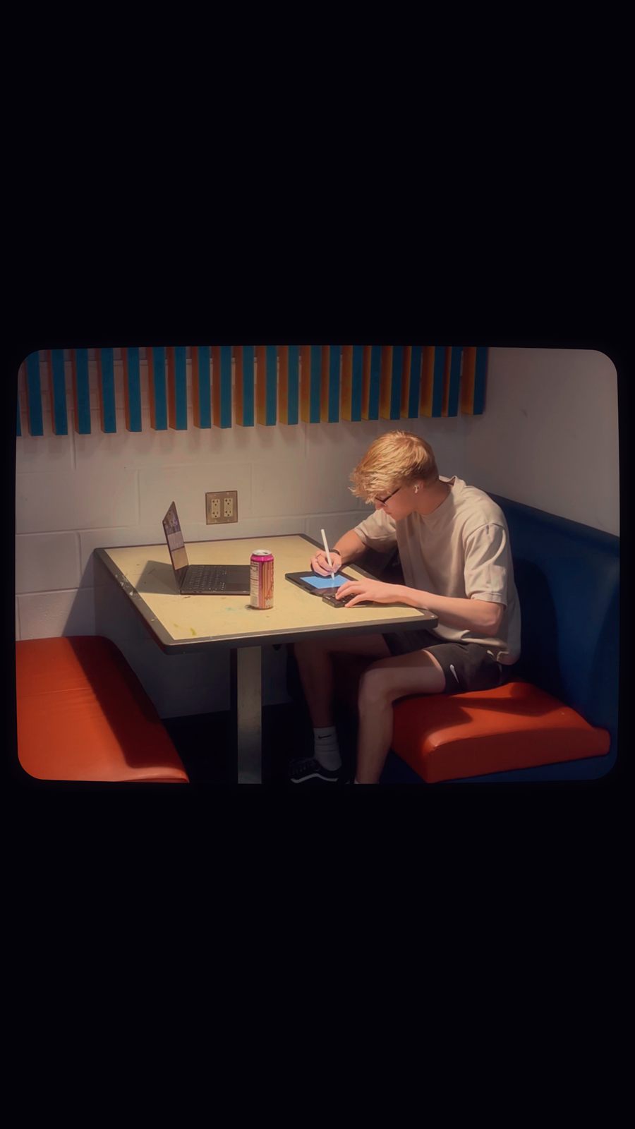 Riley Johnson sketching the mural design on a tablet at a diner booth