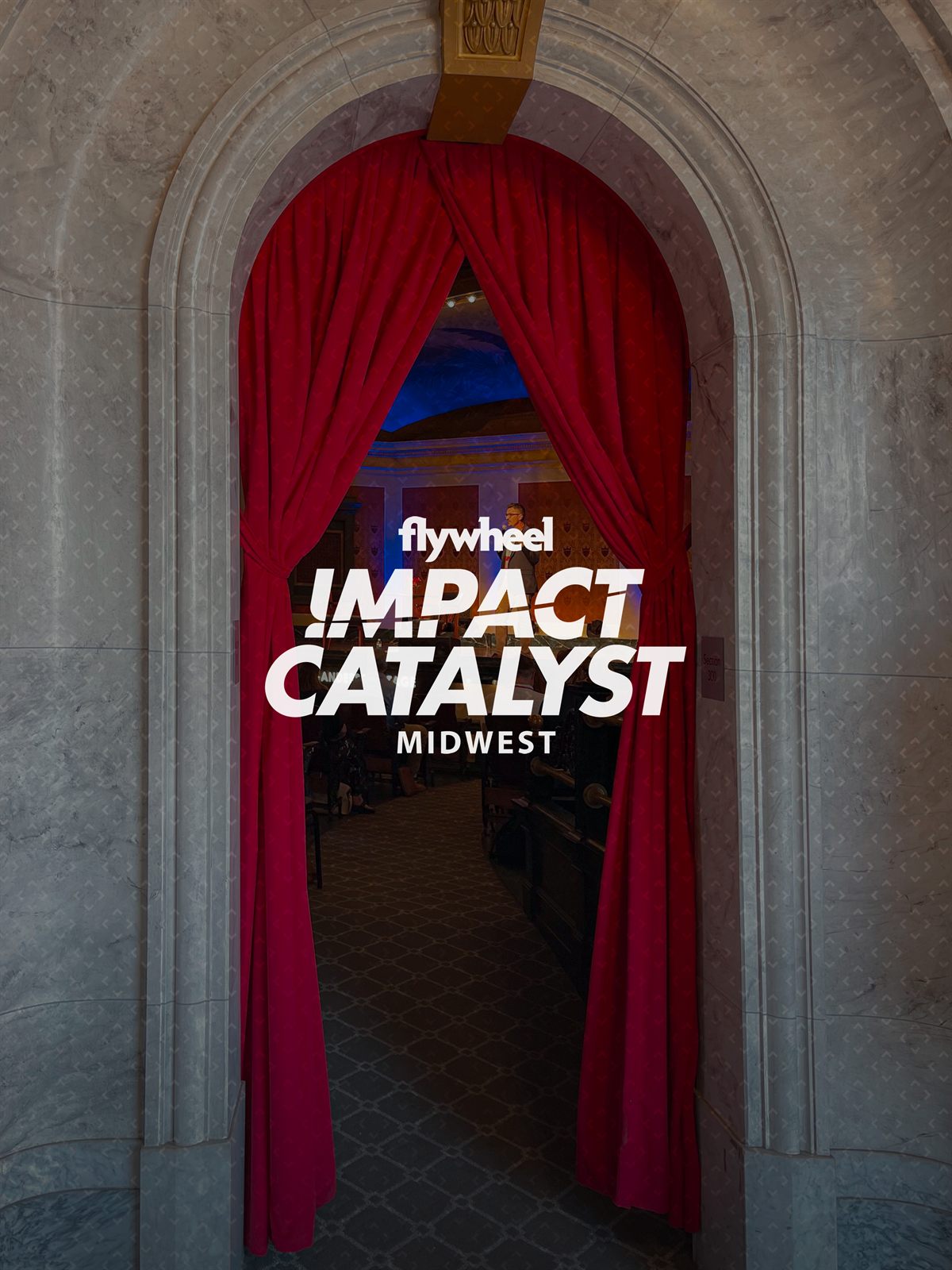 The full Flywheel Impact Catalyst Midwest lockup over a red-curtained marble archway into the hall