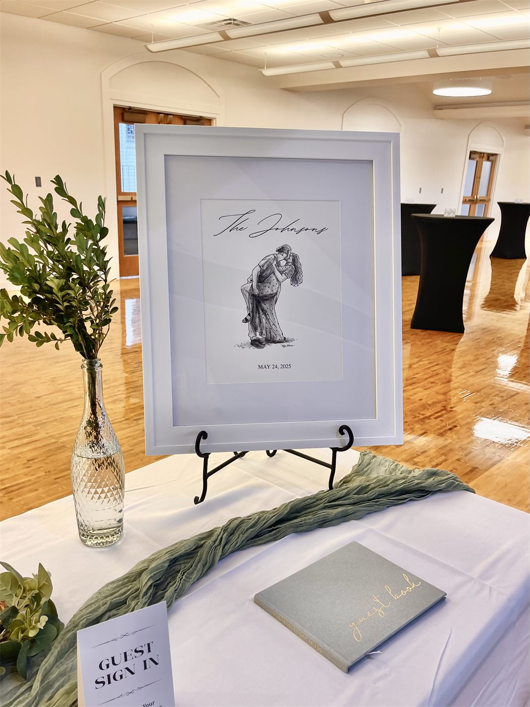 Framed ink wedding portrait of a couple on an easel at a sign-in table